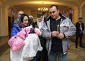 Woman mother holding baby on hands, father and relatives standing near. Ukrainian traditional ceremony christening for