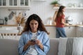 Woman mother holding smartphone buying groceries online while spending time with daughter at home