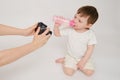 Woman mother photographs baby on photo camera, studio white backd