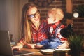 Woman mother working with a baby at home behind a computer Royalty Free Stock Photo