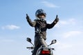 Woman on motorcycle against blue skywith thumbs up because something good has happened