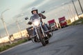 Woman motorcyclist riding on chopper with turning on headlight on asphalt urban road