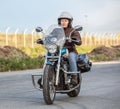 Woman motorcyclist riding solo on chopper on asphalt urban road