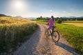 Woman on mountain bike on gravel road at sunset in summer Royalty Free Stock Photo