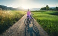 Woman on mountain bike on gravel road at sunset in summer Royalty Free Stock Photo