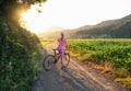 Woman on mountain bike on gravel road at sunset in summer Royalty Free Stock Photo