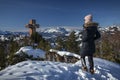 Woman at mountain cliff Buchensteinwand at Wilder Kaiser with viewpoint and sightseeing spot Jakobskreuz in winter with snow