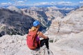 Woman mountaineer sits at the edge of a rock in Dolomites mountains, Italy, on a bright Summer day with white puffy clouds. Royalty Free Stock Photo