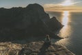 Woman mountaineer standing on rock of peak mountain at sunset. Ryten Mountain, Norway