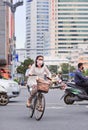 Woman with mouth cap cycles in busy traffic, Kunmin, China