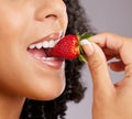 Woman, mouth and eating strawberry for natural nutrition, dieting or healthy food against a gray studio background Royalty Free Stock Photo