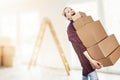 Woman moving into new apartment holding stack of cardboard boxes Royalty Free Stock Photo