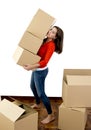 Woman moving in a new house carrying pile of cardboard boxes