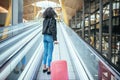 Woman in the moving walkway at the airport with a pink suitcase. Royalty Free Stock Photo