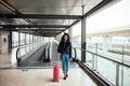 Woman in the moving walkway at the airport with a pink suitcase. Royalty Free Stock Photo