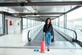 Woman in the moving walkway at the airport with a pink suitcase. Royalty Free Stock Photo