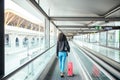 Woman in the moving walkway at the airport with a pink suitcase. Royalty Free Stock Photo