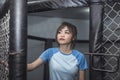 A woman Muay Thai athlete looks at the entrance of the octagon ring cage before beginning the training session