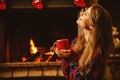 Woman with a mug by the fireplace. Young attractive woman sittin