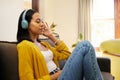 Woman, music and relax with headphones on living room sofa enjoying calm relaxation at home. Young female relaxing on a Royalty Free Stock Photo