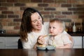 Woman nanny feeds child with healthy porridge or puree from spoon, simulating flight, in playful way. Baby feeding