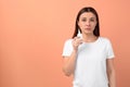 Woman with nasal spray on peach background, space for text