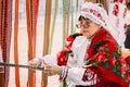 Woman in national Belarusian folk costume weaving belt. Belarus