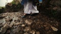 Woman in national blue bright Caucasian suit walking through stream. Rocky road
