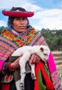 Woman in national clothing holding little lama in Sacsayhuaman