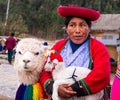 Woman in national clothing holding little lama in Sacsayhuaman