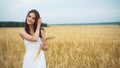 The woman in a national white shirt holds in hand the ripened wheat ears on a gold field background. harvest