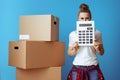 Woman near cardboard box hiding behind calculator on blue Royalty Free Stock Photo