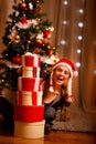 Woman near Christmas tree looking out from gifts Royalty Free Stock Photo