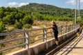 A woman near the railings of a dam of Algar del Palancia on a sunny day