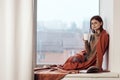 woman near the window with a plaid cup of hot drink rest Royalty Free Stock Photo