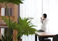 Woman near window in room decorated with plants. Home design Royalty Free Stock Photo