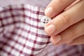 Woman with needle stitching on button to shirt