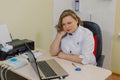 Woman neurologist pondered at the computer in the office of the clinic.