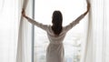 Woman in night robe gown pulling opening lace curtains. Royalty Free Stock Photo