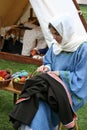 A woman in a Norman costume mending a garment at The reenactment of The Battle of Hastings