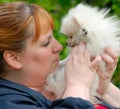 Woman Nose to Nose with a White Pomeranian Puppy