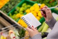 Woman with notebook in grocery store, closeup. Shopping list on paper. Royalty Free Stock Photo