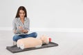 Woman with notebook near mannequin at first aid