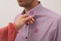 Woman noticed lipstick kiss marks on her husband`s shirt against white background, closeup