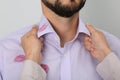 Woman noticed lipstick kiss marks while straightening her husband`s shirt against white background, closeup