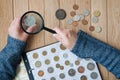 Woman-numismatist views coins from a coin album through a magnifying glass. Top view Royalty Free Stock Photo