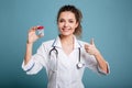 Woman nurse in lab coat showing pills and thumb up isolated Royalty Free Stock Photo