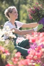 Woman in nursery admiring flowers she holding