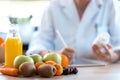 Woman nutritionist doctor writes the medical prescription for a correct diet on a desk with fruits, pills and supplements Royalty Free Stock Photo