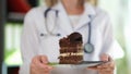 Woman nutritionist holding in hands piece of chocolate cake